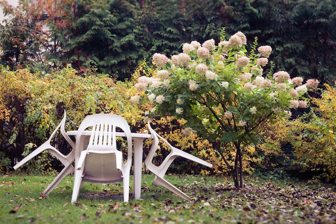 White plastic outdoor chairs and tables in autumn garden