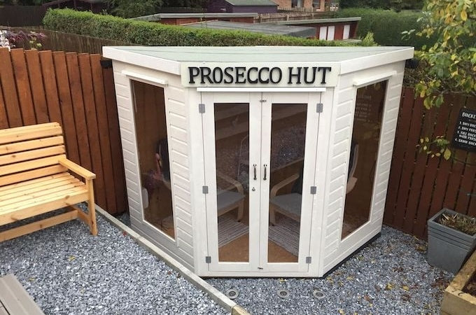 White painted summerhouse with sign saying 'Prosecco Hut'