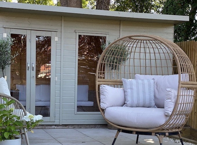 Rattan garden furniture in front of painted Waltons summer house