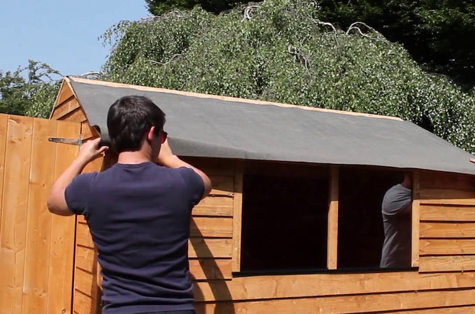 rolling out roof felt on a shed roof