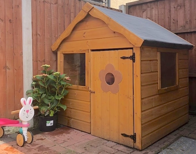Small wooden playhouse with flower door decal