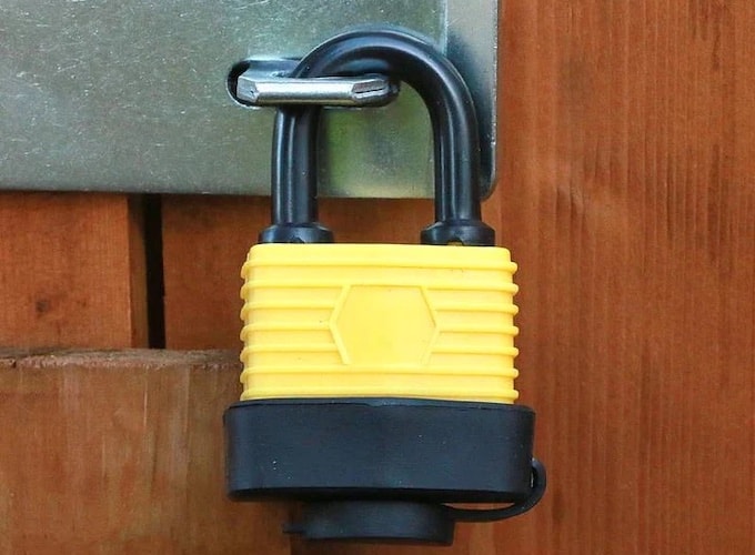 Yellow weatherproof padlock against wooden shed