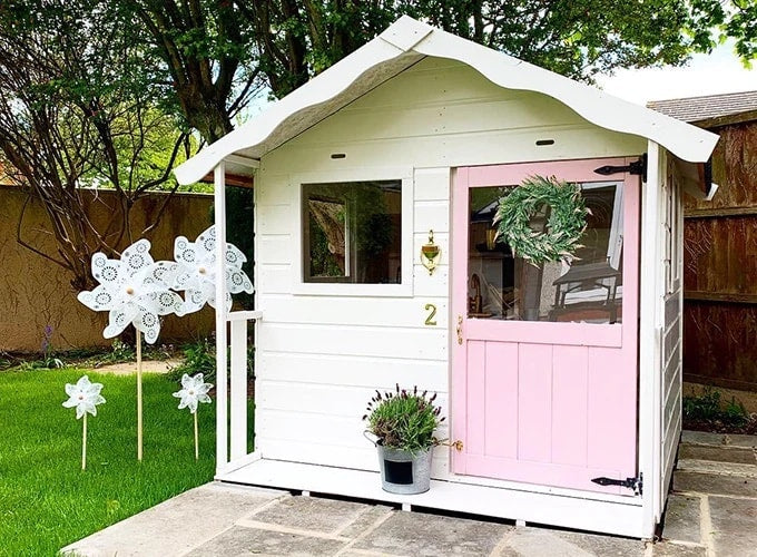 White and pink Waltons playhouse in garden