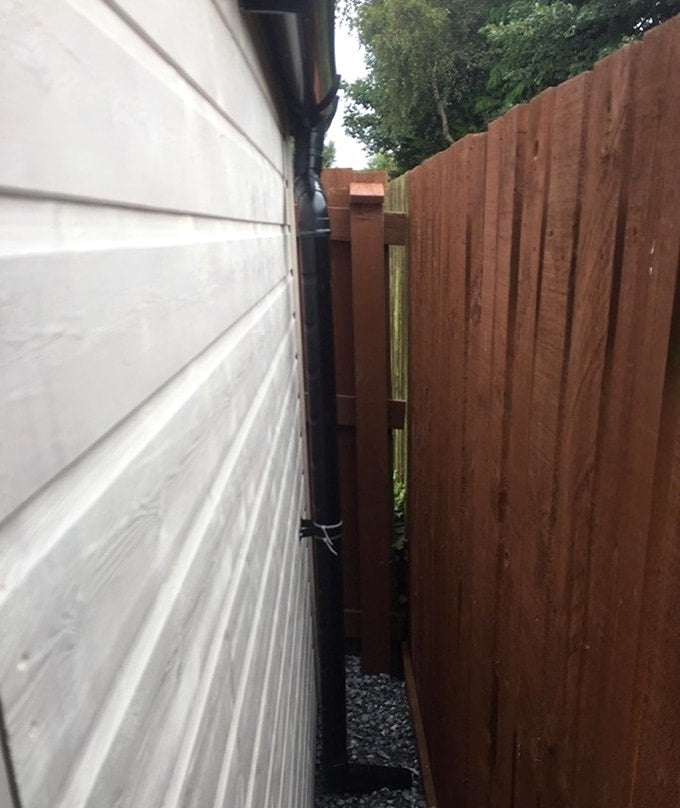 Black drainpipe against white Waltons summer house