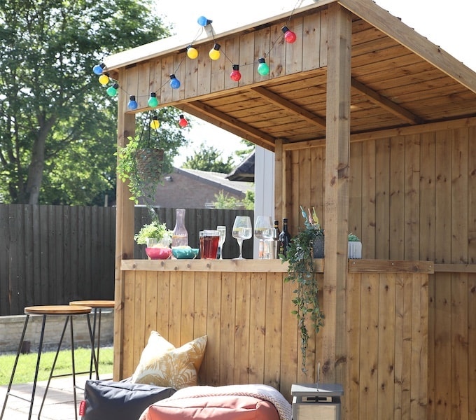 Wooden garden bar with multicoloured fairy lights and outdoor soft furnishings