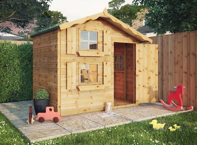Two storey wooden playhouse with toys outside