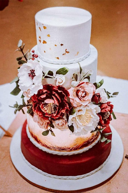 a beautiful wedding cake plus some foliage fully covered with pink and blush sugar blooms and green blooming branches is wow