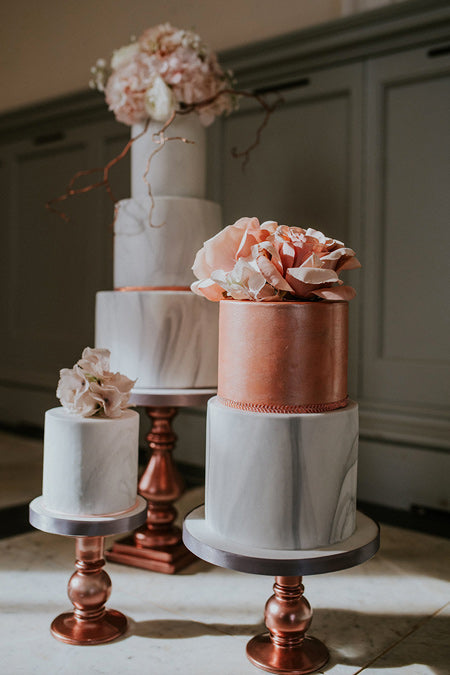 a marble texture wedding cake with rose gold decor and blush roses and twig is a very elegant choice