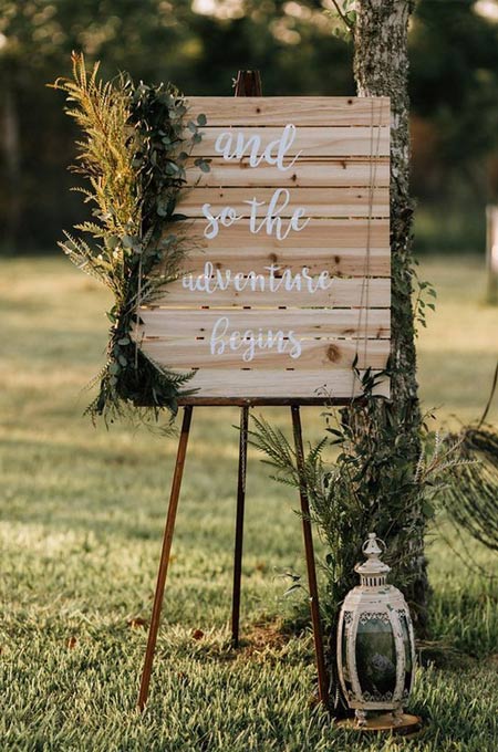 simple backyard wedding decor with a wooden board sign, greenery, dried blooms, or a candle lantern
