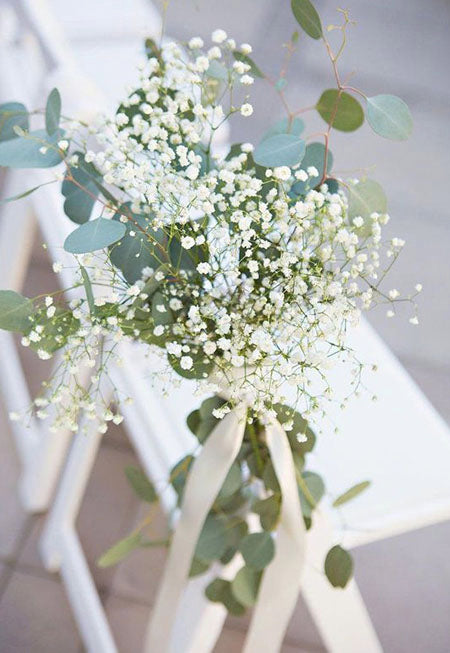 wedding ceremony aisle chairs decorated with baby's breath and white ribbon