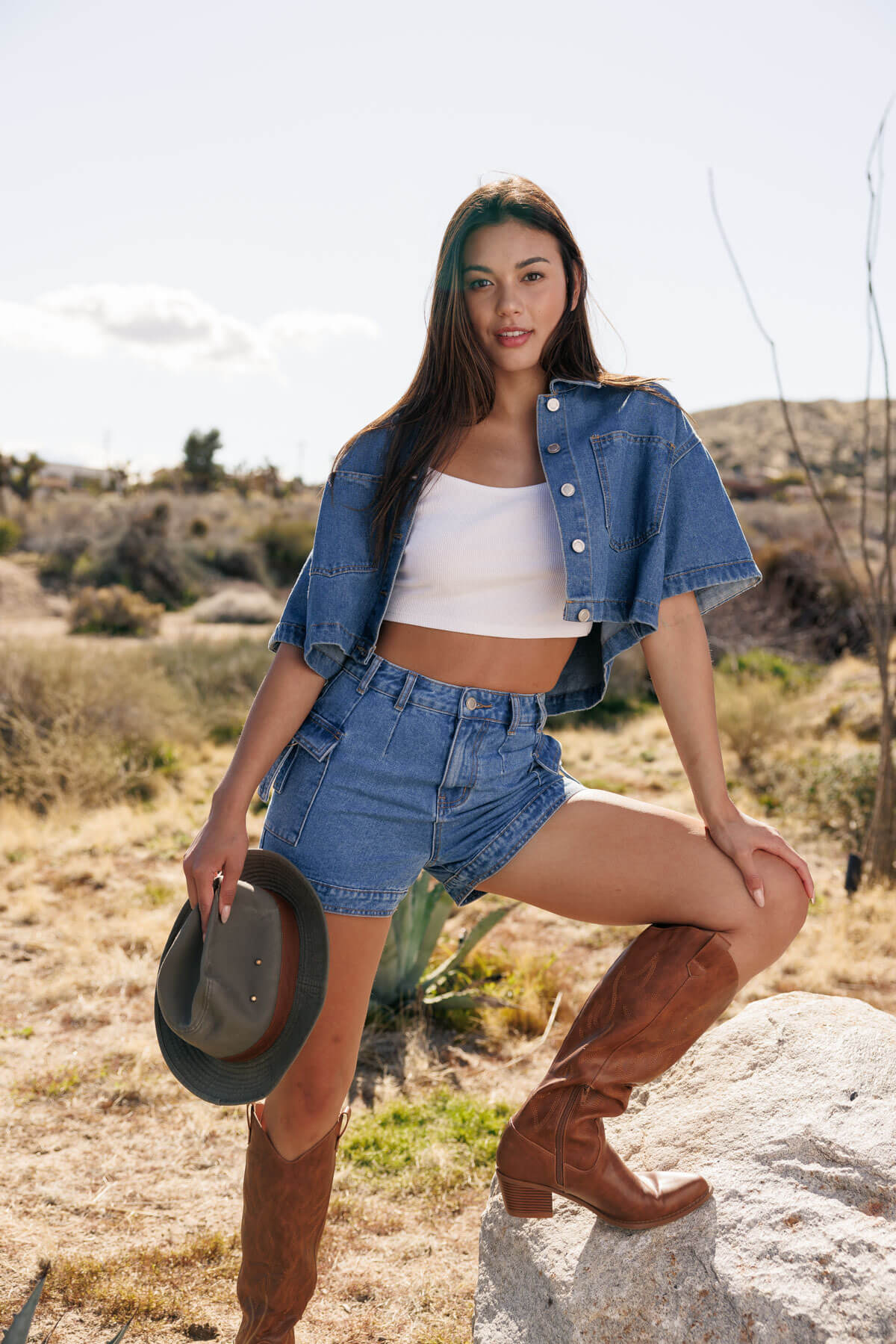 A woman wearing cowboy boots and denim standing in a desert