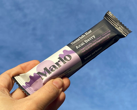 Athlete holding Marlo Nourish Bar Acai Berry flavour towards the sky