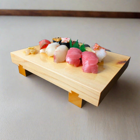 Wooden sushi tray displaying an assortment of sushi rolls and nigiri against a muted blue-grey background.