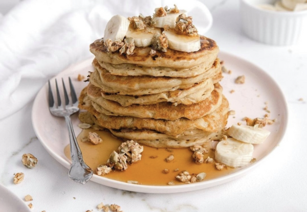 A plate of pancakes topped with bananas and ratio crunchy bars. and ratio crunchy bars