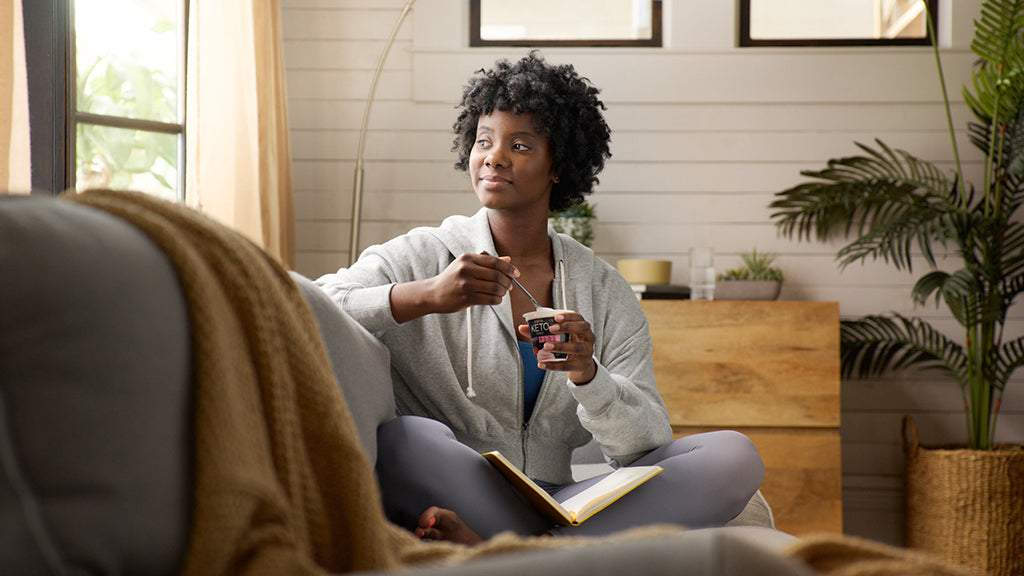 woman eating a :ratio dairy snack on the couch