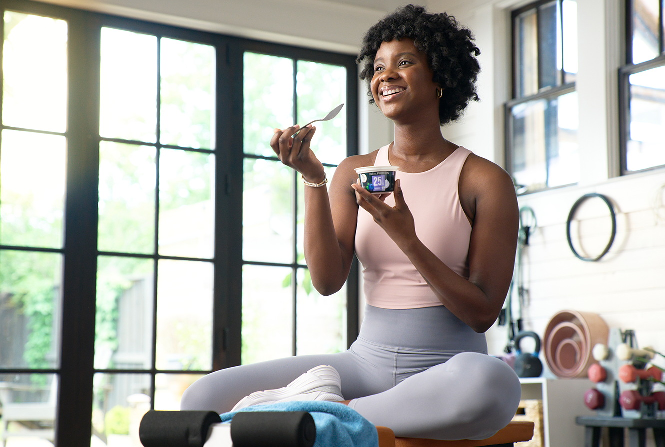 woman in home gym enjoying ratio protein yogurt