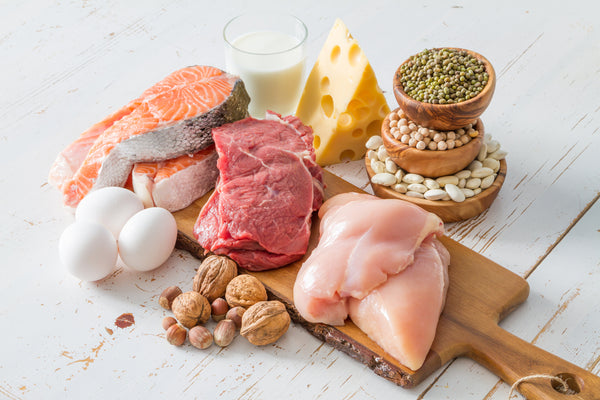 proteins on a wooden board: salmon, eggs, nuts, meat, cheese, milk, seeds