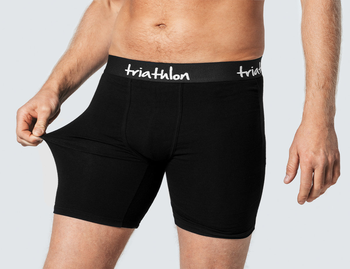 Close-up of a man wearing black boxer briefs with a triathlon logo waistband.
