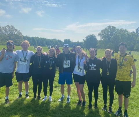 young adults standing in a row holding their finishers medal for a country side 10k race