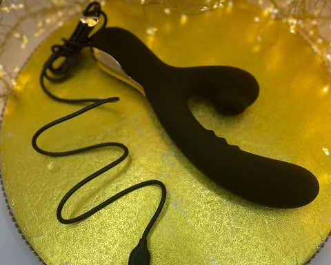 a black rechargeable vibrator with a black recharging cable on a gold circle