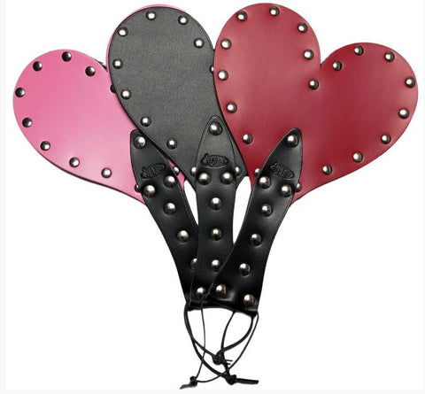 Three handmade heart-shaped leather paddles. Pink, black and red.