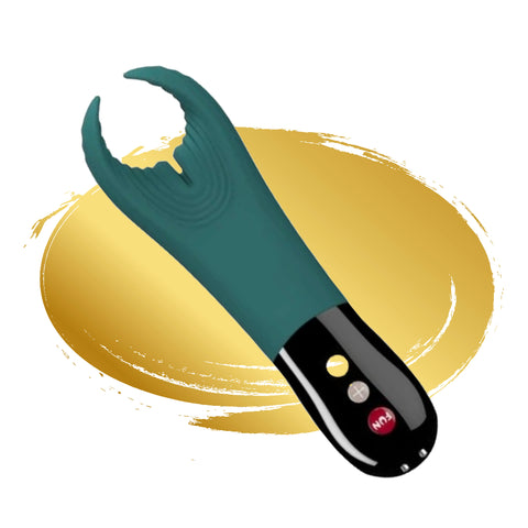 A teal Manta penis massager on a gold background