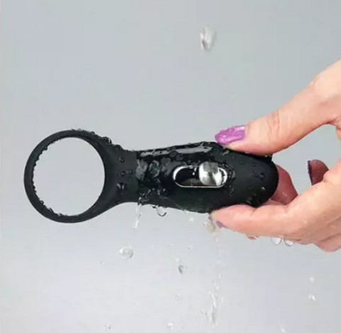 a hand holding a black vibrating cock ring