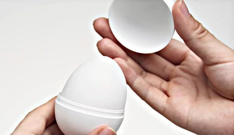 A hand removing the top from a Tenga Egg. 