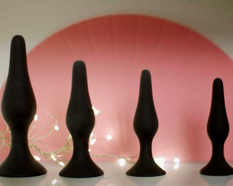 A set of four black butt plugs in graduating sizes