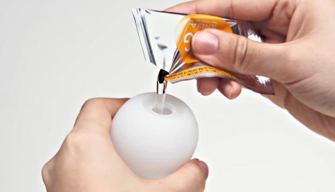 A hand pouring lube into a Tenga Egg