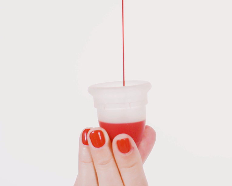 a hand holding a mooncup with blood