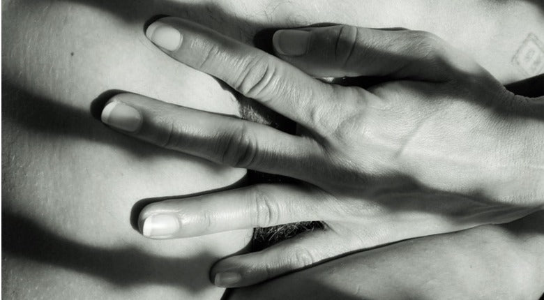 black & white close up of a hand covering pubic hair