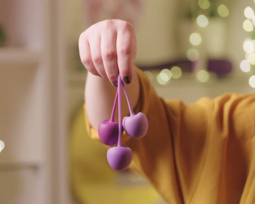 a hand holding three love balls in varying shades of purple