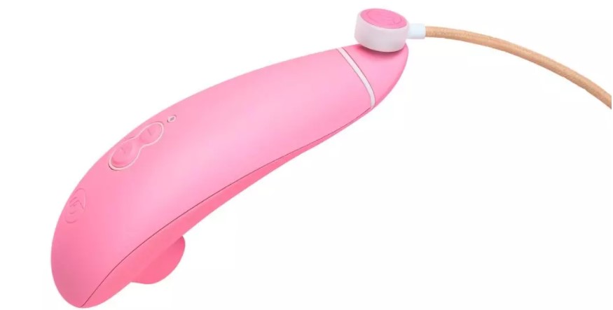 a womanizer eco suction vibrator in pink with a charging cable