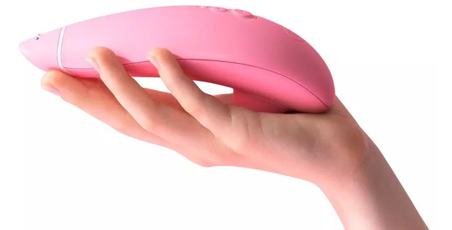 A hand holding a womanizer eco sex toy in pink