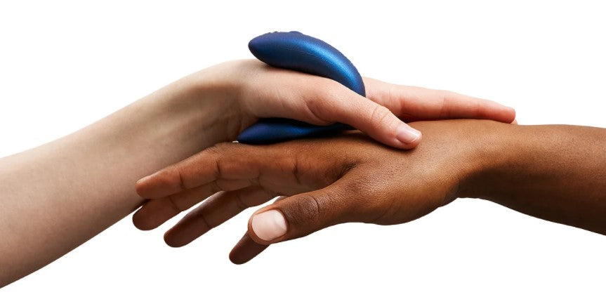 A brown-skinned hand and a light-skinned hand holkding a blue couples vibrator together
