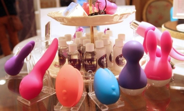 A table full of sex toys in a variety of shapes and colours. 