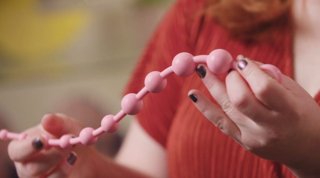 a pair of hands holding a string of anal beads