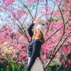 A woman standing amongst cherry blossoms