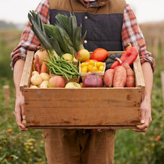 A farmer proudly holding a box of fresh produce