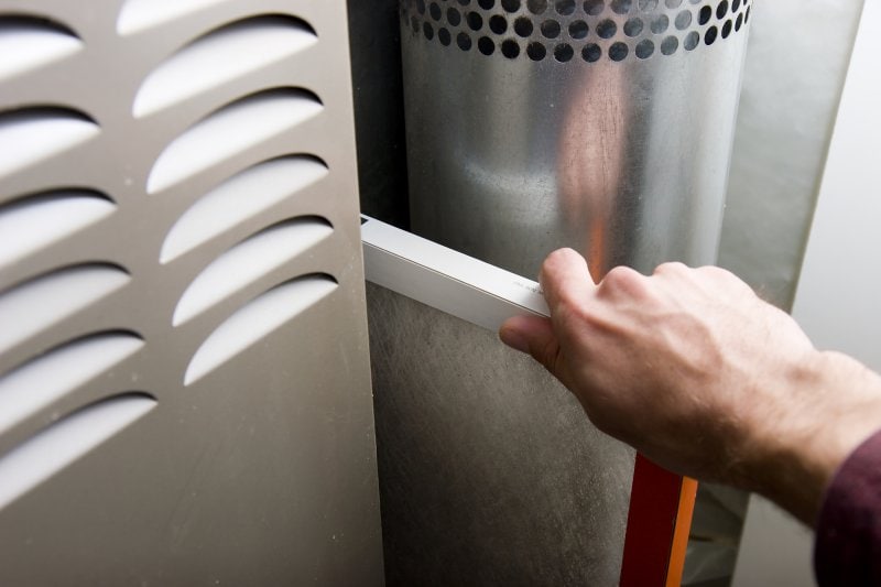 A person replacing a furnace filter.