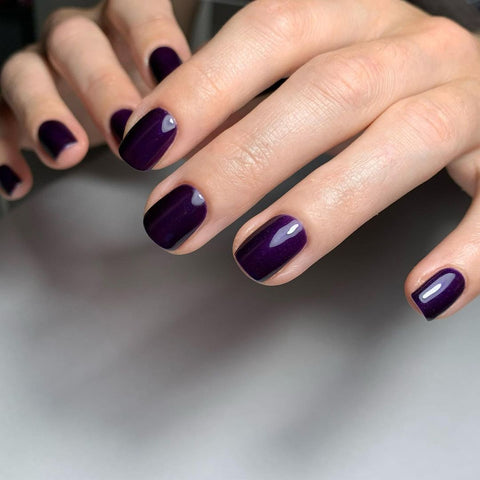 Deep purple nail polish on a manicured hand