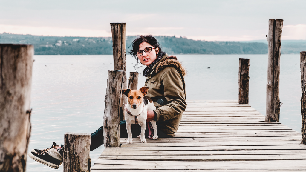 Woman on a dock with her dog, totally chillin' after taking Revogreen Muscle & Joints
