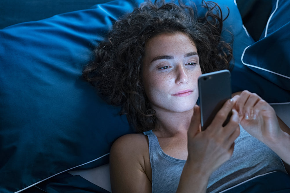 Insomniac woman looking at her phone at 3:00 a.m.