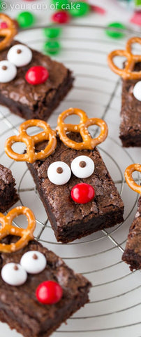 Brownies that have pretzels, eyes and a red chocolate to represent a reindeer - Giddy Vibes