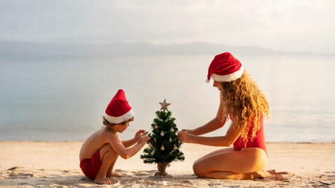 woman and child decorating christmas tree on the beach