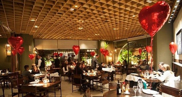 Restaurante em estilo rústico decorado com balões de coração nas mesas.