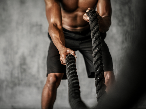 Muscular man working out with thick ropes