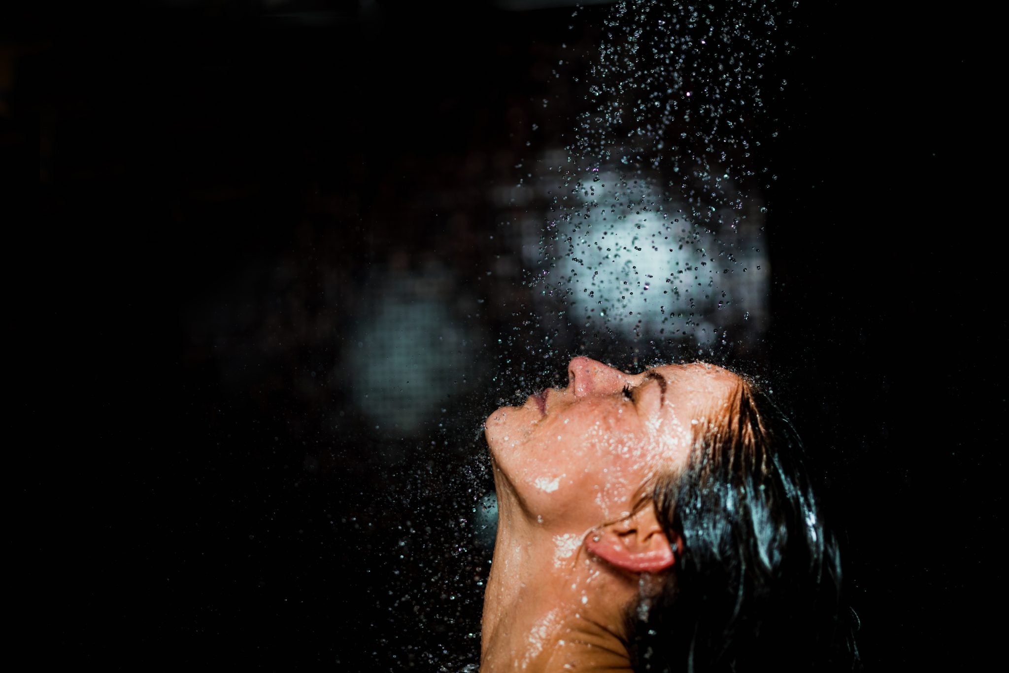 Piękna kobieta bierze prysznic na czarnym tle