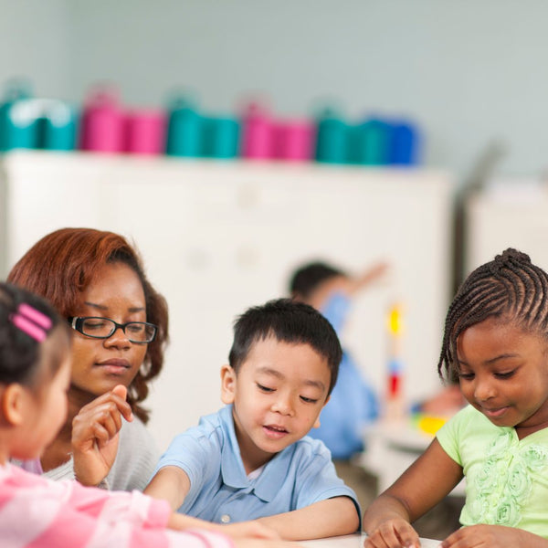 Diverse children playing in a classroom as the teacher considers social and cultural backgrounds of the children for individualized learning through Developmentally Appropriate Practice.